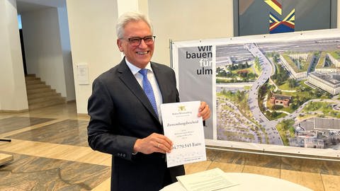 Ulms Oberbürgermeister Gunther Czisch hält den Förderbescheid des Landes hoch. Er freut sich über die Förderung von rund 105 Millionen Euro.