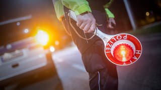 Ein per Haftbefehl gesuchter Mann flieht in Senden vor einer Polizeikontrolle. Das Symbolbild zeigt einen Polizisten mit Halte-Schild.