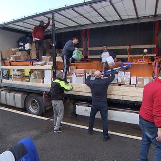 Freiwillige Helfer und Helferinnen beladen einen Sattelzug mit Hilfsgütern.