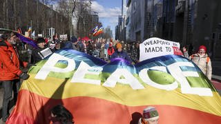 Eine große "Peace"-Friedensfahne weht vor einer Menge von Menschen - bei der "Aufstand für Frieden"-Kundgebung in Berlin.  