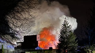 Qualm und Feuerschein eines brennenden Gebäudes. Der bei einem Brand in einem Dachdeckerbetrieb in Laichingen (Alb-Donau-Kreis) entstandende Qualm war weithin zu sehen. 