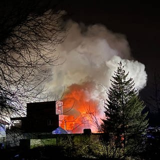 Qualm und Feuerschein eines brennenden Gebäudes. Der bei einem Brand in einem Dachdeckerbetrieb in Laichingen (Alb-Donau-Kreis) entstandende Qualm war weithin zu sehen. 