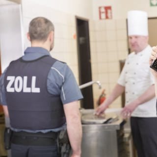 Zwei Einsatzkräfte des Ulmer Hauptzollamtes kontrollen einen Gastronomiebetrieb. Bei der ganztägigen Aktion ging es um die Einhaltung von Mindestlöhnen. 