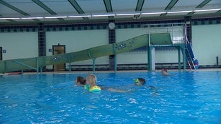 Eine Familie schwimmt im großen Becken des Hallenbads in Oberkochen, dass gerade wieder aufgemacht hat. 