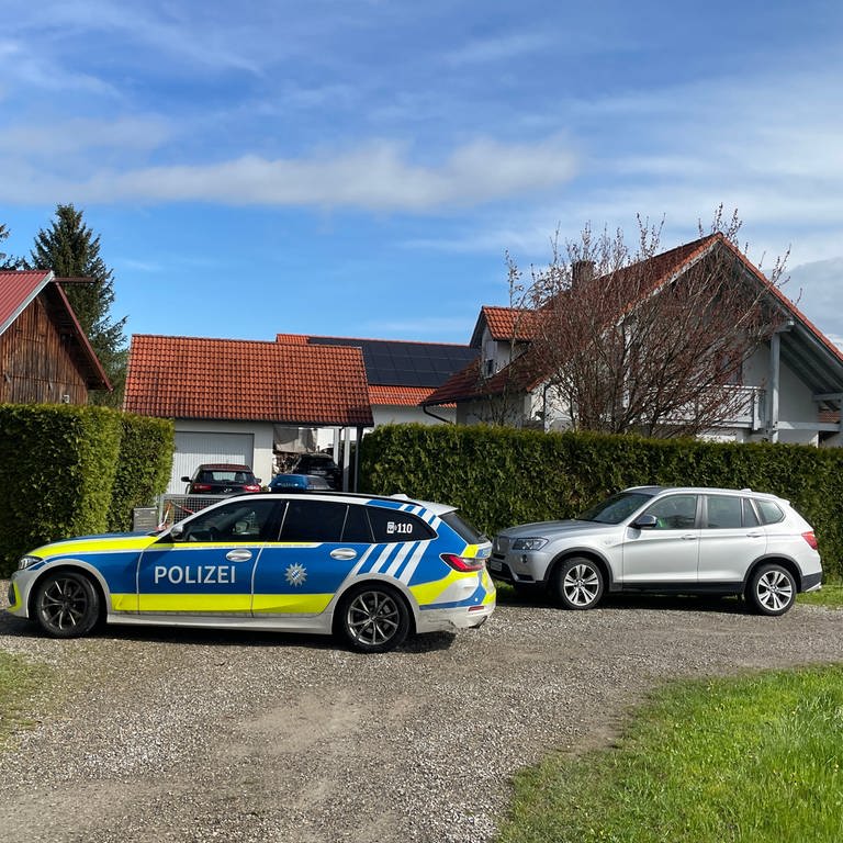 Ein Polizeifahrzeug vor einem Einfamilienhaus. Die Kripo Neu-Ulm hat am Freitag erste Ermittlungsergebnisse im Fall des getöteten Ehepaars aus Altenstadt bekannt gegeben. Das Ehepaar war am 22. April tot in seinem Haus entdeckt worden. Die Polizei suchte das Umfeld nach Spuren ab. (Archivbild). 