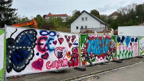 Abgerissene Flüchtlingsunterkunft in Illerkirchberg im Alb-Donau-Kreis. Ein Bauzaun umgibt das Gelände, der Name des Mädchen, umringt von Herzen und Blumen ist darauf gemalt. 