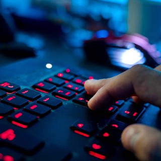 Ein Mann sitzt am Rechner und tippt auf einer Tastatur. In Ulm treffen sich bis Freitag Hacker und Hackerinnen zum Finale der Cyber Security Challenge Germany.