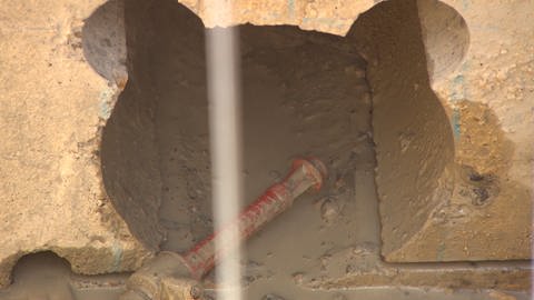 Eine Seilsäge schneidet durch einen Stein und wird bewässert