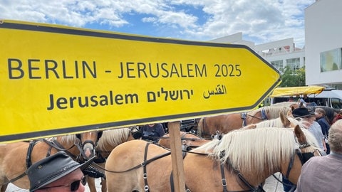 Gelbes Verkehrsschild mit der Aufschrift Berlin-Jerusalem. 4.800 Kilometer wollen die Mitglieder des Vereins "Friedensglocke" mit Pferden und Glocke von Berlin nach Jerusalem fahren - 2025 soll es losgehen.