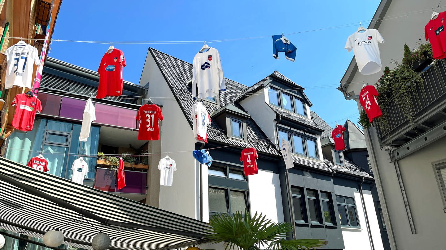 Fußball-Trikots hängen an einer Leine zwischen Häusern.Fußball-Trikots hängen an einer Leine zwischen Häusern in Heidenheim - auch in der Stadt ist die Vorfreude auf die Bundesliga-Premiere des FCH groß und die Fans fiebern dem Auftakt der Saison entgegen.