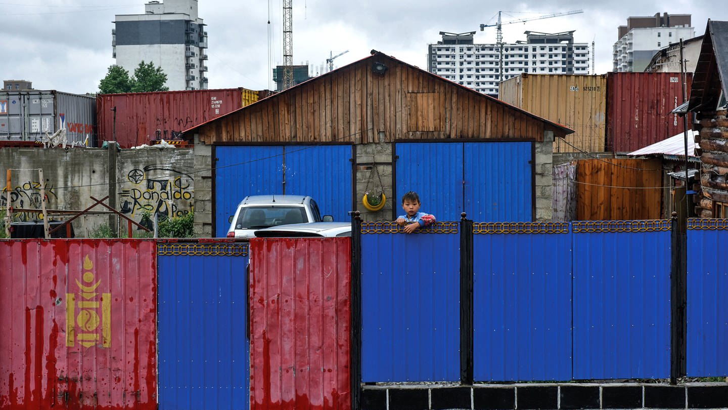 Ein Junge schaut über einen bunten Bretterzaun - die Hälfte der Mongolen lebt in der Hauptstadt Ulaanbaatar, viele auch in Vorstadtvierteln, den sogeannten Ger-Distrikts.