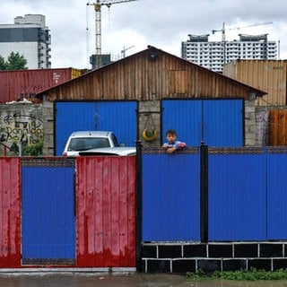 Ein Junge schaut über einen bunten Bretterzaun - die Hälfte der Mongolen lebt in der Hauptstadt Ulaanbaatar, viele auch in Vorstadtvierteln, den sogeannten Ger-Distrikts.