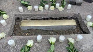 Kerzen und Blumen vor der neuen Stolperschwelle in Aalen-Wasseralfingen - Zum Gedenken an KZ-Häftlinge hat der Künstler Demnig am Samstag (26.8) eine sogenannte Stolperschwelle verlegt. Anders als Stolpersteine wird sie an eine Gruppe von Opfern erinnern.