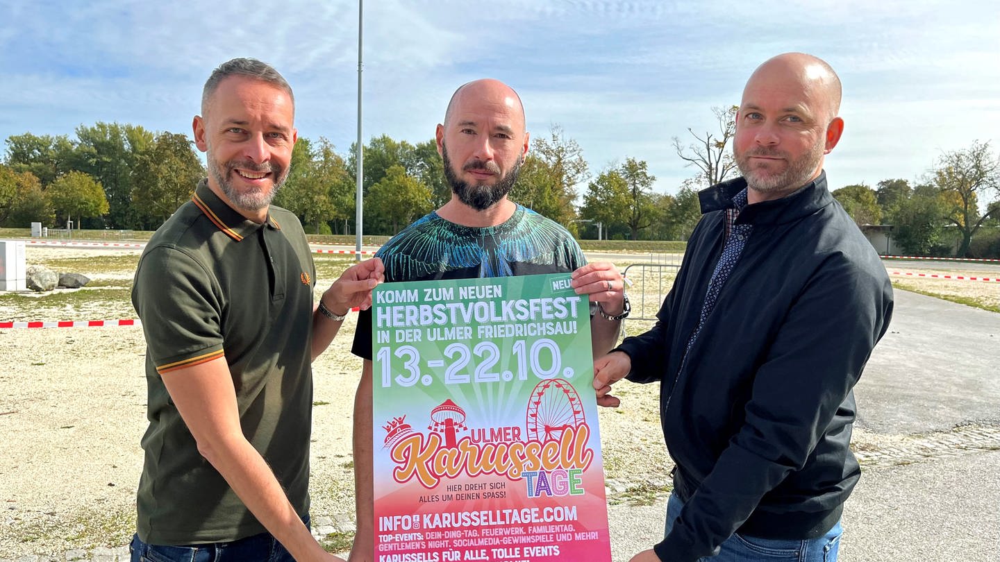 Drei Männer halten ein Plakat: Auf dem Festplatz in Ulm finden im Oktober  die 1. Ulmer Karusseltage statt