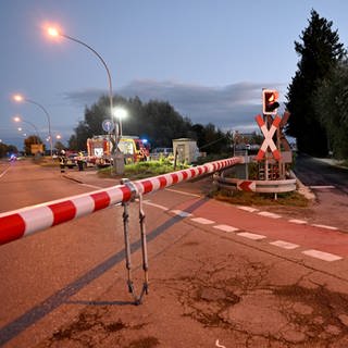 Einsatzkräfte von Polizei und Rettungsdiensten an einem Bahnübergang: Tödlicher Bahnunfall bei Neu-Ulm: Ein 20-Jähriger kam am Samstag bei einem Zusammenstoß mit einer Regionalbahn ums Leben.