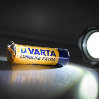 Eine verbeulte Batterie wird von einer Taschenlampe angestrahlt. Beim kriselnden Batteriehersteller VARTA aus Ellwangen läuft es weiterhin nicht rund. 