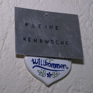 Ein Schild mit der Aufschrift "Kleine Kehrwoche". Die Kehrwoche in vielen Mietshäusern in Aalen wird abgeschafft, deshalb hängt dieses Schild vor den Haustüren der Wohnungsbau Aalen bald nicht mehr.