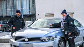 Zwei Mitarbeiter des Ordnungsamtes stehen auf einem Parkplatz in Giengen an der Brenz im Landkreis Heidenheim. Wer derzeit richtig parkt, bekommt Schokolade als Knöllchen.