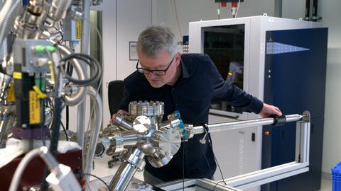 Ein Mann steht an einer Vorrichtung in einem Labor. Das Team von Batterieforscher Professor Max Fichtner (Foto) arbeitet im Labor des Helmholtz-Instituts Ulm an der besseren Tauglichkeit von E-Autos im Winter. 