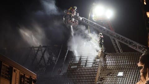 Brand eines Bauernhofes in Langenau. Die Feuerwehr ist mit mehr als 100 Einsatzkräften vor Ort. Sie spritzt Löschwasser von zwei Drehleitern aus in den abgebrannten Dachstuhl.