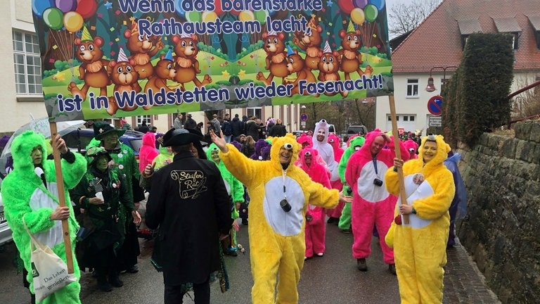 Fasnets-Narren halten ein großes Schild......