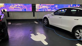 Ein Auto steht in einem Parkhaus an einer E-Ladesäule. Im Boden ist ein Sensor verbaut, der misst ob der Parkplatz belegt ist. Er ist Teil der Smart City Projekte der Stadt Ulm.