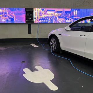 Ein Auto steht in einem Parkhaus an einer E-Ladesäule. Im Boden ist ein Sensor verbaut, der misst ob der Parkplatz belegt ist. Er ist Teil der Smart City Projekte der Stadt Ulm.