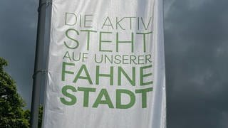 Eine Fahne am Schlossberg in Heidenheim mit der Aufschrift "Die aktiv steht auf unserer Fahne Stadt".Die Fahnen am Schlossberg in Heidenheim sind Teil der neuen Marketingkampagne. Der Slogan sorgt bei vielen für Verwirrung.