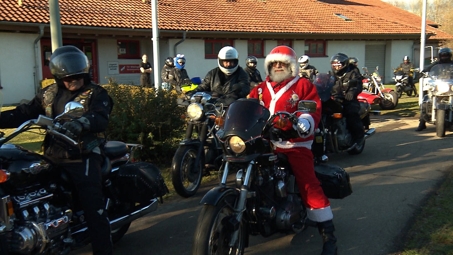 Charles Heilman fährt im Weihnachtsmannkostüm auf seiner Harley los, gefolgt von der Motorradkolonne