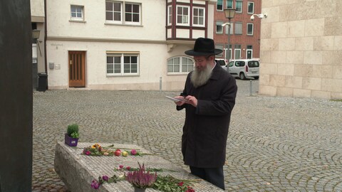 Ein Mann mit Bart und Hut betrachtet einen Stein mit Blumen. Zeichen der Solidarität mit Israel - der Ulmer Rabbiner Shneur Trebnik, Mitglied im Rat der Religionen, betrachtet vor der Synagoge die Blumen und Briefe der Menschen.