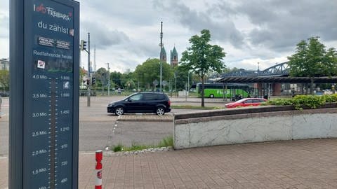 Eine Säule in Freiburg, die die Fahrradfahrenden zählt. Im Hintergrund ein Bus und Autos. 