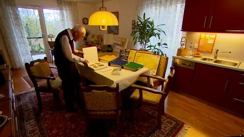 Helmut Weiss, 95 Jahre alt, steht an seinem Esstisch und blättert im Fotoalbum der Familie.