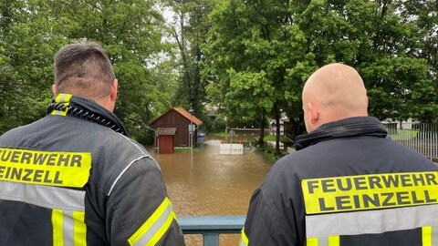 Hochwasser an der Lein: Feuerwehrleute schauen auf den über die Ufer getretenen Fluss