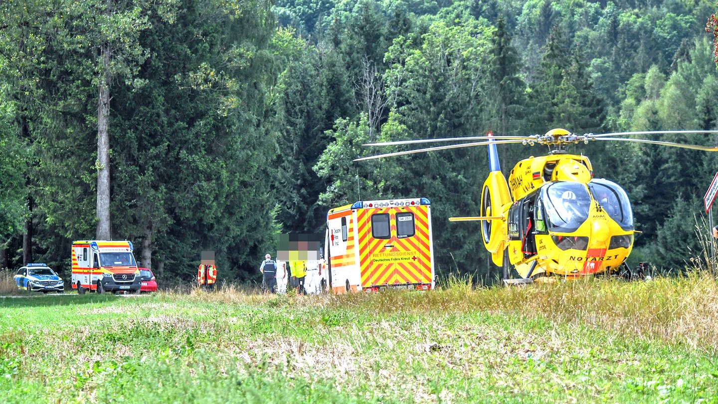 Ein Rettungshubschrauber und Rettungskräfte auf einem Weg an eiem Waldstück: Ein Waldarbeiter ist am Mittwoch bei Ellwangen von einer umstürzenden Fichte schwer verletzt worden.