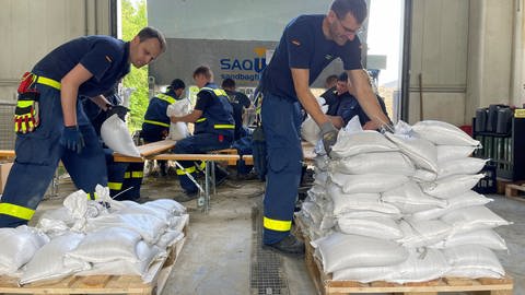 Befüllen, Zuschnüren, verladen: Die Sandsäcke, die das Technische Hilfswerk im Logistikzentrum in Ulm vorbereitet hat, sollen in den überfluteten Gebieten in Baden-Württemberg und Bayern das Hochwasser zurückdrängen.