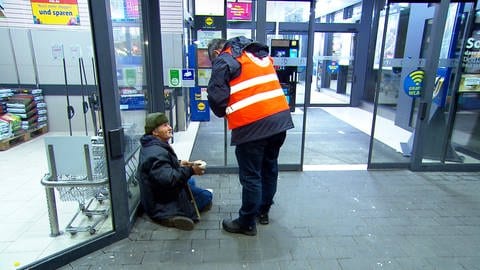 Ein DRK-Mitarbeiter reicht einem Obdachlosen in einer Passage in Ulm eine warme Suppe. Der Ulmer Kältebus ist derzeit jeden Abend unterwegs, um Wohnungslosen zu helfen. 