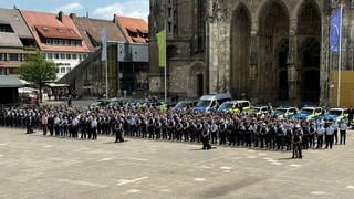 Polizistinnen und Polizisten auf einem Platz. Die Polizei in Ulm gedachte um 11:34 Uhr auf dem Ulmer Münsterplatz mit einer Schweigeminute des getöteten Polizisten in Mannheim. 