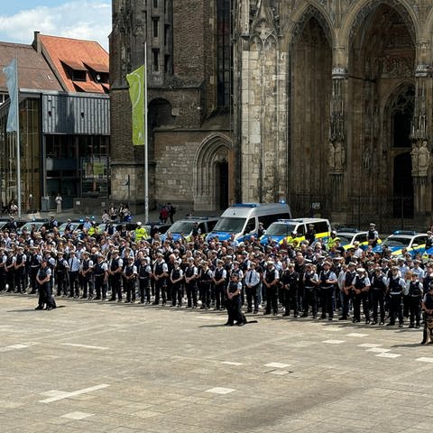 Polizistinnen und Polizisten auf einem Platz. Die Polizei in Ulm gedachte um 11:34 Uhr auf dem Ulmer Münsterplatz mit einer Schweigeminute des getöteten Polizisten in Mannheim. 