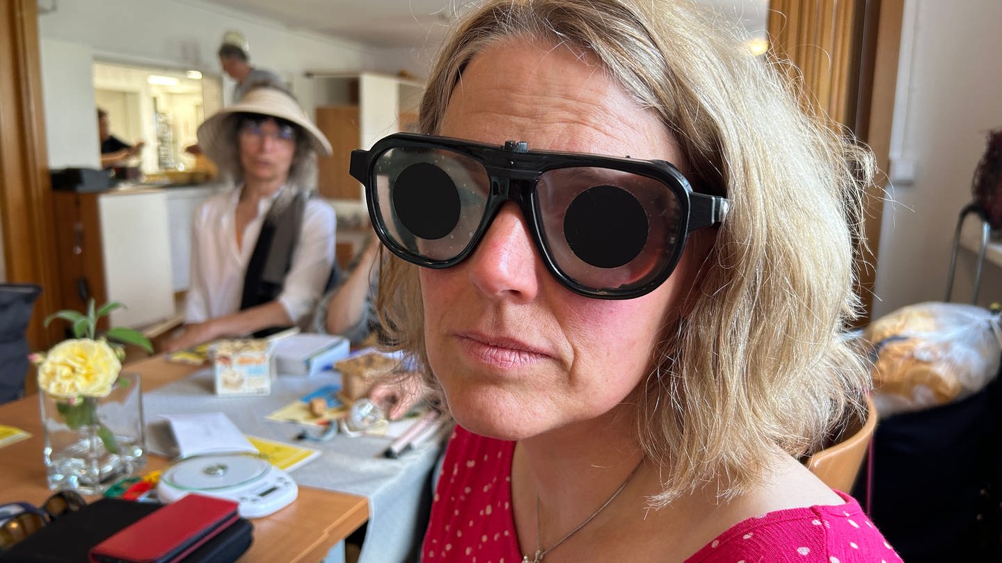 Eine Frau blickt durch eine mit Folie abgedeckte Brille.