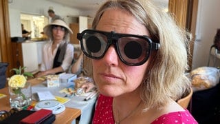 Eine Frau blickt durch eine mit Folie abgedeckte Brille. 