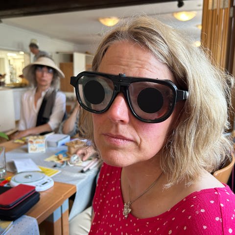 Eine Frau blickt durch eine mit Folie abgedeckte Brille. 