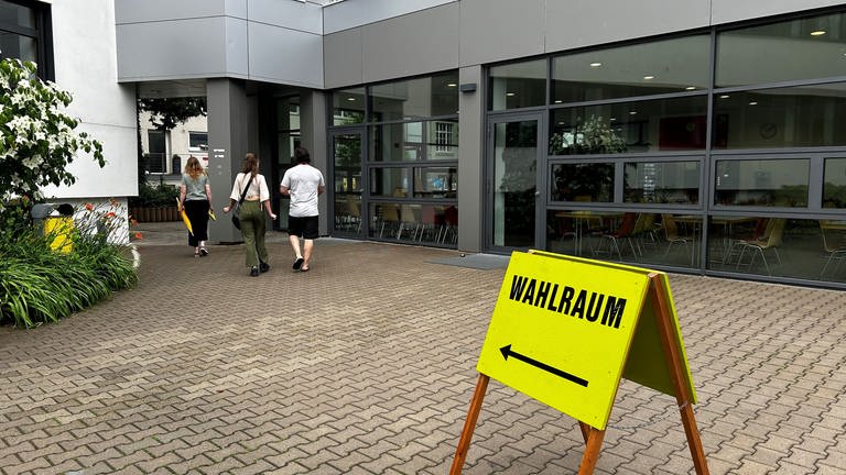 Ein Schild zum Wahllokal: In Ulm sind mehr als 90.000 Menschen zur Wahl aufgerufen. Stand 14 Uhr haben laut der Landeswahlleiterin 25,7 Prozent der Menschen in Baden-Württemberg gewählt. Weniger als zu diesem Zeitpunkt vor fünf Jahren.