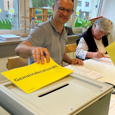 Wahlhelfer nehmen in einem Ulmer Wahllokal Stimmzettel entgegen.