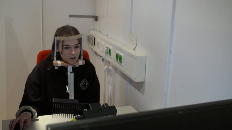 Eine Probandin sitzt am Eye-Tracking-Computer, ihr Kopf ist fixiert - eine ältere Technologie, um Blicke zu analysieren. 