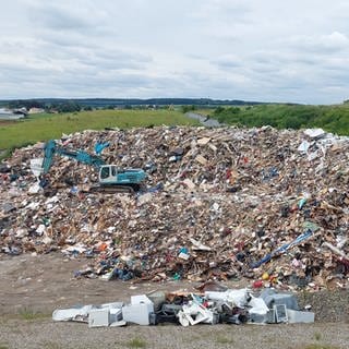 Ein riesiger Sperrmüllberg mit einem Bagger, der fast darin verschwindet: Im Kreis Günzburg sind inzwischen 25.000 Kubikmeter Hochwasser-Müll gesammelt worden.