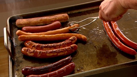 Würstchen auf einem Grill: Drei Metzger aus der Region liefern unter anderem die Würtchen, die jeden Tag auf dem Grill landen.