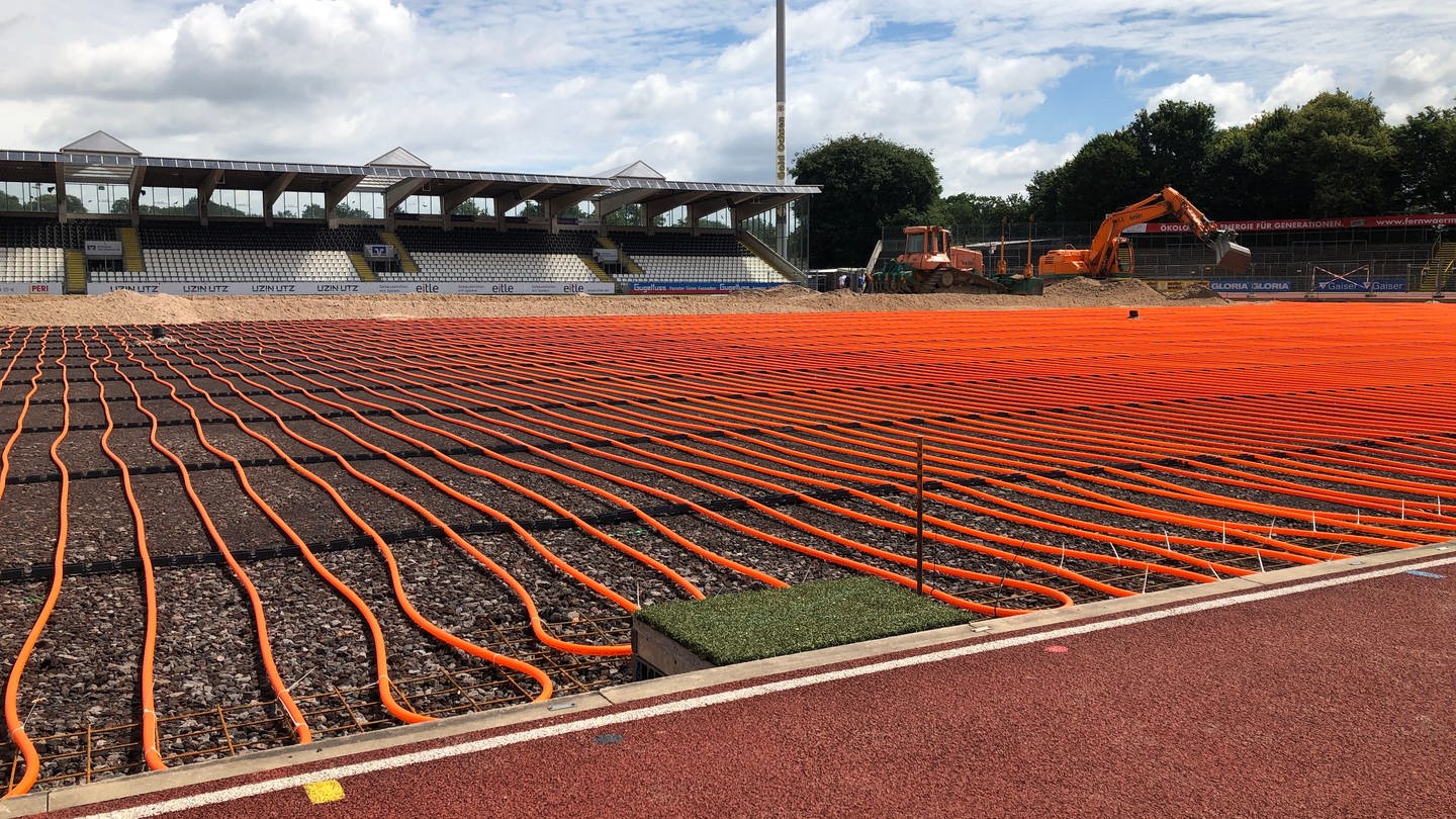 Zahlreiche orangefarbene Schlauchleitungen in einem Stadion.
