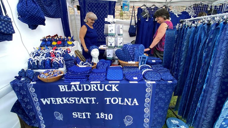 Stand voller blaugedrückter Kleidung auf dem Markt der Donauländer beim 13. Internationalen Donaufest.