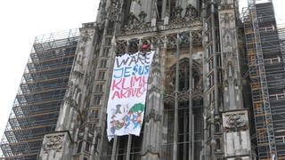 Ein Transparent mit der Aufschrift «Wäre Jesus Klimaaktivist?» ist an der Fassade am Ulmer Münster zu sehen. 