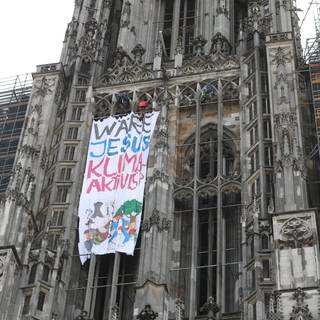 Ein Transparent mit der Aufschrift «Wäre Jesus Klimaaktivist?» ist an der Fassade am Ulmer Münster zu sehen. 